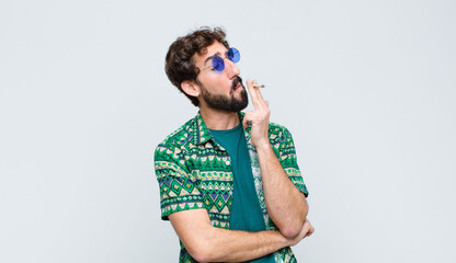 young hippie man smoking a joint against white wall
