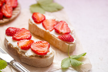 Strawberries sandwiches with cream cheese and on paper, light background