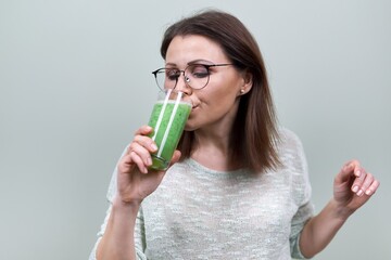 Mature woman with green vegetable smoothie drink, woman drinking juice