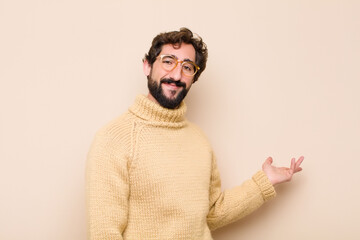 young cool man feeling happy and cheerful, smiling and welcoming you, inviting you in with a...