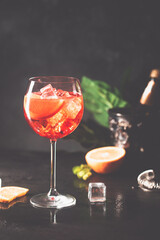 Aperol spritz cocktail in glass with fresh orange on dark background