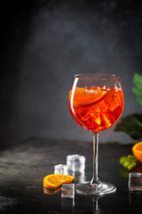 Aperol spritz cocktail in glass with fresh orange on dark background