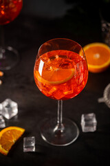 Aperol spritz cocktail in glass with fresh orange on dark background