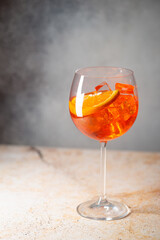 Aperol spritz cocktail in glass with fresh orange on gray background