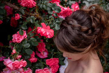 Naklejka premium Portrait of pretty bride dressed wedding white dress, make up and hairstyle posing at the background flowers roses wall at the morning with wind in hair.