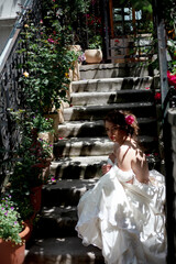 Obraz premium Alone luxury bride wearing stylish wedding white dress waiting in the stairs of the house with flowers
