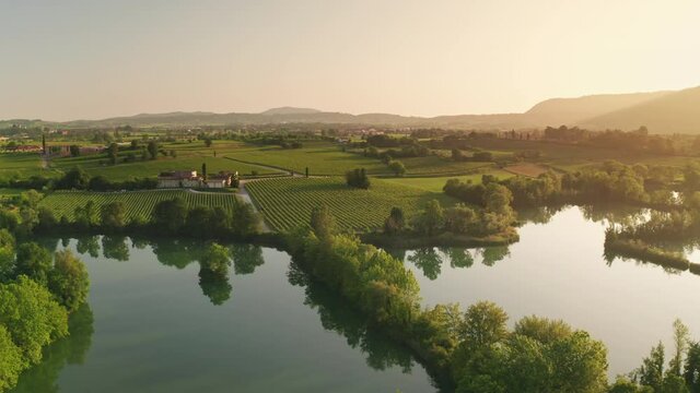 Aerial Drone View of Franciacorta Region in Northern Italy.
High View of Vineyard Green Fields and Scenic Pond.
Picturesque Landscape with Colorful Warm Sunset Sky.