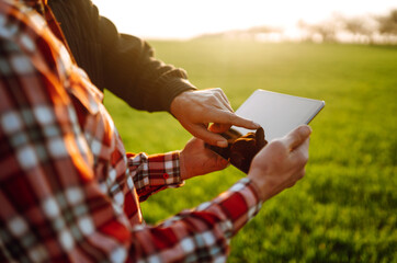 Farmers reading and discussing a report in a tablet computer on an agriculture field at sunset....