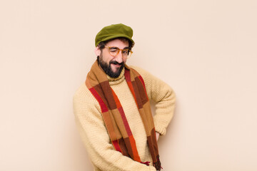 young cool bearded man looking happy and friendly, smiling and winking an eye at you with a...