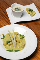 Stew chicken curry in coconut sauce and creamy vegetable soup served on the restaurant table