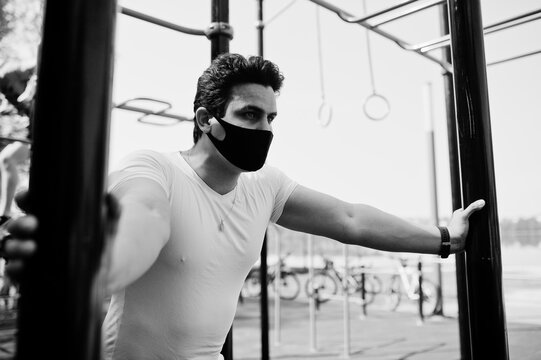 Portrait Sports Arabian Man In Black Medical Face Mask Doing Workout Exercises In Outdoor Gym Place During Coronavirus Quarantine.