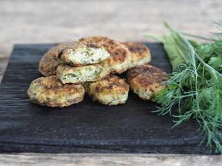 Healthy vegetarian and dietary food. Vegetable and fish cutlets with greens on a wooden background.