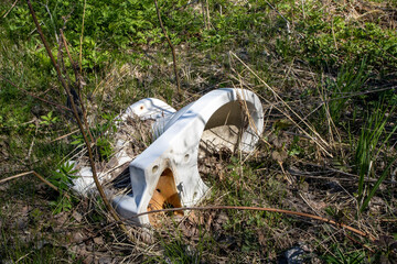 dumped old white toilet bowl outdoors