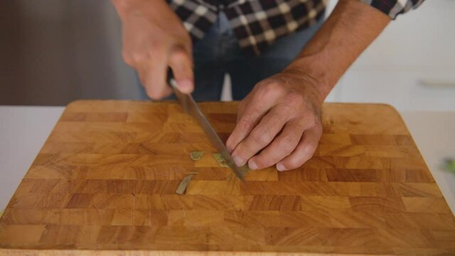 Close up of cook hands cutting dry leaves of laurel, close-up cooking, precise movements with sharp knife on cutting board, healthy lifestyle concept