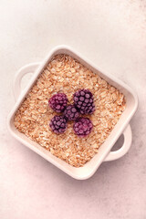 Granola in a white bowl with fresh berries on a light background in a minimalistic style