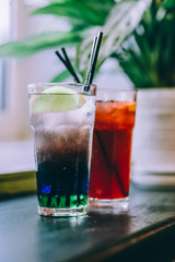 red cocktail and multi-colored cocktail with lemon on the table