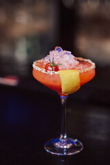 red cocktail with cherry tomato and sesame seeds at the bar