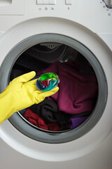 Woman put capsule with liquid powder into washing machine with laundry.