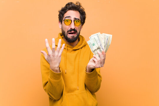 young crazy cool man with dollar banknotes against orange wall
