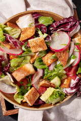 Traditional Middle Eastern Fattoush salad with pita bread,fresh vegetables and lemon sumac dressing on dark gray background top view closeup.Healthy vegetarian food