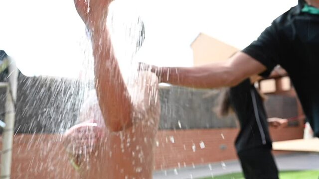 11 year old boy has fun splashing water in outdoor shower