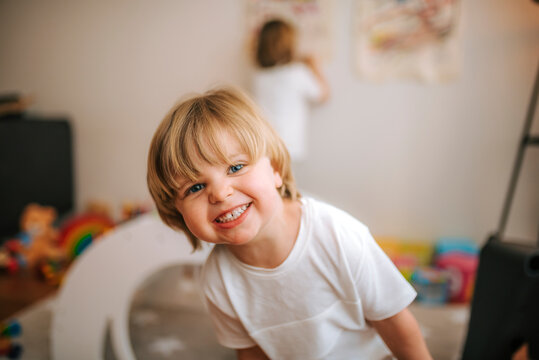 little blond boy laughs looking at camera at home. fun at home family at home