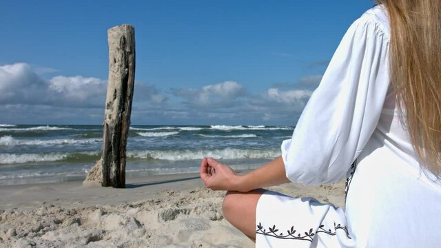 Woman meditating on the beach in the lotus position.