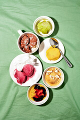 Bowls of various vegan sugar free sorbet ice cream scoop on green background top view.Healthy dessert concept