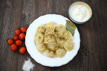 Dumplings on a wooden table with herbs tomatoes