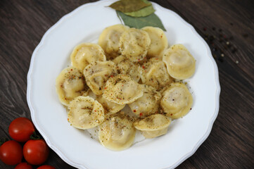 Dumplings on a wooden table with herbs tomatoes