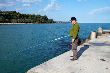 a fisherman with a fishing rod stands on the pier
