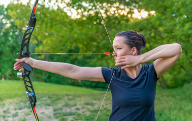 archery, young woman with an arrow in a bow focused on hitting a target