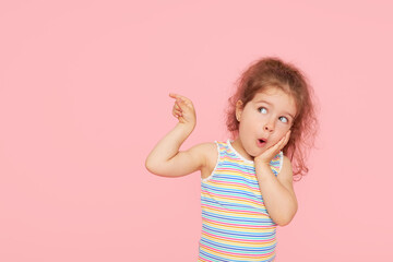Portrait of surprised cute little toddler girl child over pink background. Looking at camera....