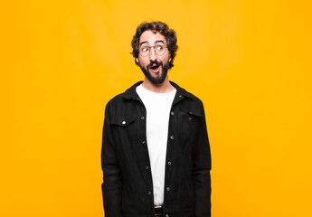young crazy handsome man feeling shocked, happy, amazed and surprised, looking to the side with...