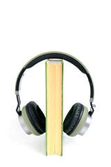 Headphones and a book on a white background. Listen to audiobooks online.