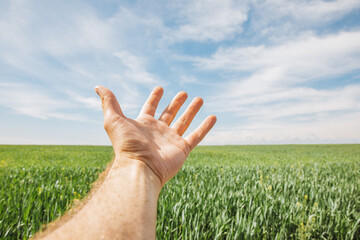 white man points his hand to a green field and a blue sky with clouds