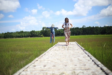 A woman standing on a wooden bridge in a rice field