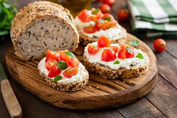 Italian antipasti bruschetta with tomato, basil and ricotta cheese on wooden serving board. Closeup...