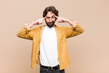 young crazy cool man with a serious and concentrated look, brainstorming and thinking about a challenging problem against flat wall