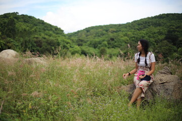 A woman sitting on a stone in a meadow