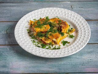 Fast nutritious breakfast with omelet, tomatoes and fresh herbs on a white plate
