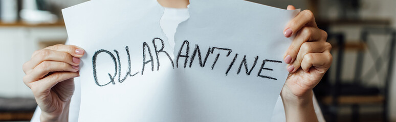 Cropped view of woman tearing card with quarantine lettering, panoramic crop