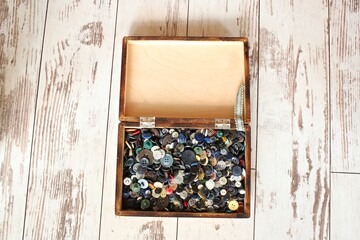 Many buttons of different size and color in a small wooden box