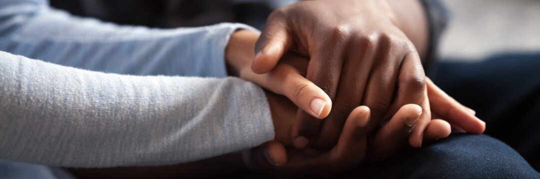 Close up photo african couple in love, woman man holding hands. Gesture of sincere feelings, compassion, apology, reliable friend, share pain or happiness. Horizontal banner for website header design