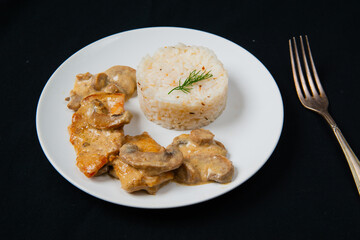 Chicken Breast in Creamy White Wine and Mushroom Sauce. With a silver fork in right.