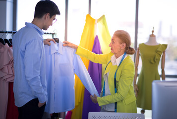 Older women tailors will recommend shirts for male customers in the tailor shop.
