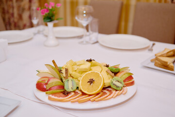 Plate with sliced fruits on servered buffet table at luxury wedding reception, copy space. Catering banquet table in restaurant. Restaurant presentation, food, party concept