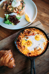 Large cast iron skillet with fried eggs and crossaint