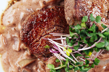Closeup fillet mignon steak onion sauce greens