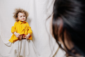 Portrait of a girl with bright sincere baby emotions. Little curly girl posing for a photo